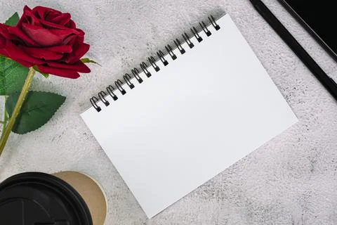 Note book with disposable coffee cup, pen, smartphone and roses on marble t.. Stock Photos