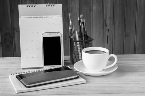 Note book,smart phone,coffee cup,and stack of book with calendar on wooden ta Stock Photos