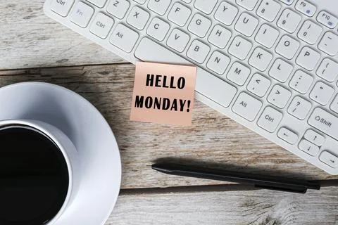 Note with hello monday stick on white keyboard on wooden desk with coffee. Stock Photos