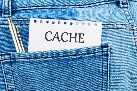 A note labeled cache is placed in the pocket of a pair of blue denim jeans, s Stock Photos