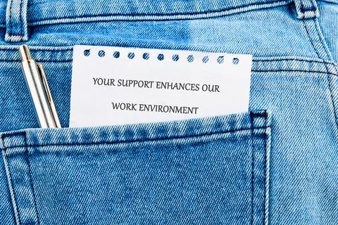 A note with the message Your support enhances our work environment is nestled Foto stock