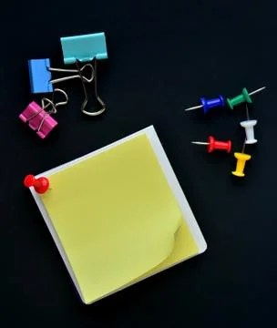 Note pad, pushpin and binder clip on black background Stock Photos