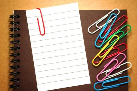 Note paper clip on brown notebook with colorful paperclips Stock Photos