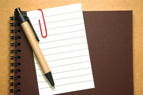Note paper clip on notebook with pen on brown paper cardboard background Stock Photos