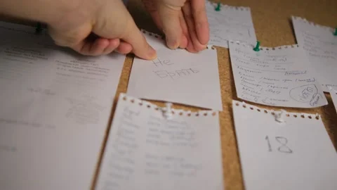 Note paper on a cork board. Notes, stickers, reminders. Selective focus. Men's h Stock Footage 148388759