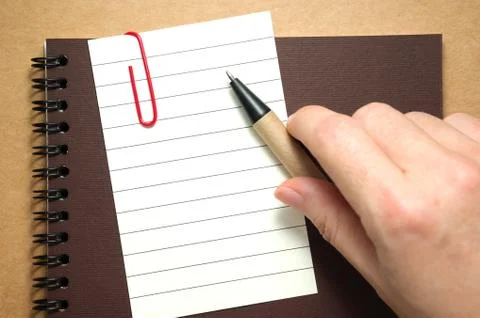 Note paper on notebook with hand and pen on kraft cardboard background Stock Photos
