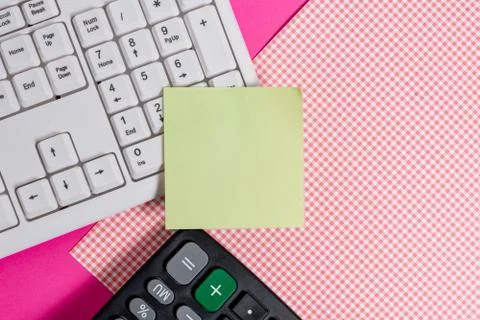 Note sheet sticked to computer keyboard near patterned fabric and calculator Foto stock
