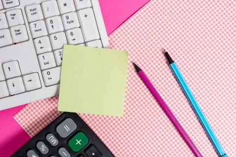 Note sheet sticked to computer keyboard near patterned fabric and stationary Foto stock