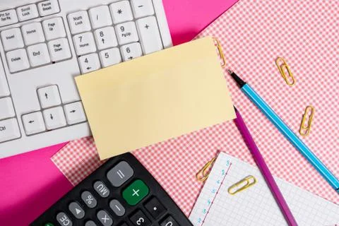 Note sheet sticked to computer keyboard near patterned fabric and stationary Foto stock