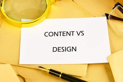 A note on a table shows the words Content vs Design. Nearby are papers, a f.. Stock-Fotos