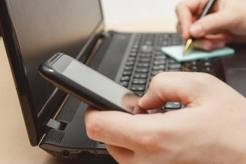 Note taking while use smartphone and laptop computer Stock Photos