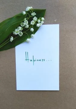 Note with text on white paper and a small bouquet of lilies of the valley Foto stock