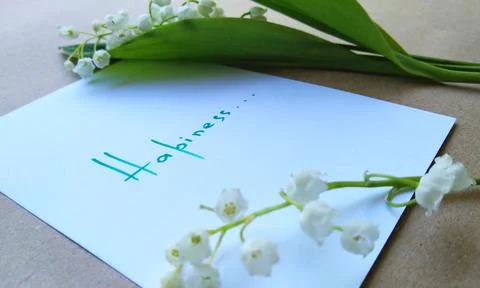 Note with text on white paper and a small bouquet of lilies of the valley Stock Photos