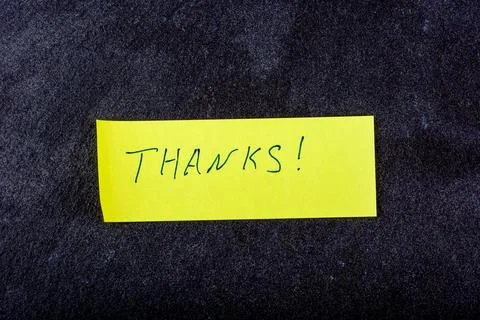 Note with Thanks on a yellow sticky note against a dark background. Stock Photos