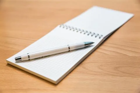 A notebook and ballpoint pen lying on a wooden table. Stock Photos