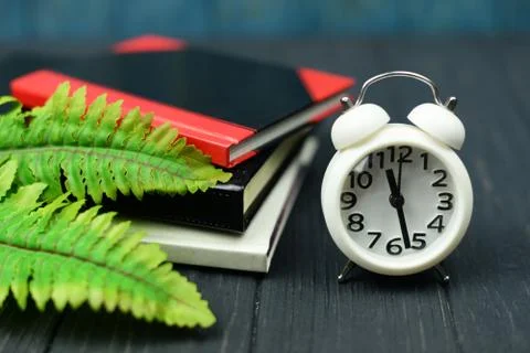Notebook and clock alarm clock white on a wooden blue background Stock Photos