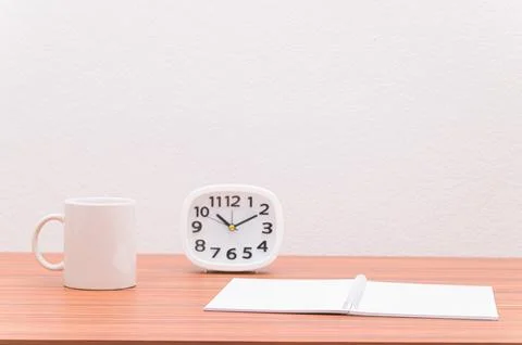 The notebook and the clock are on the table. Stock Photos