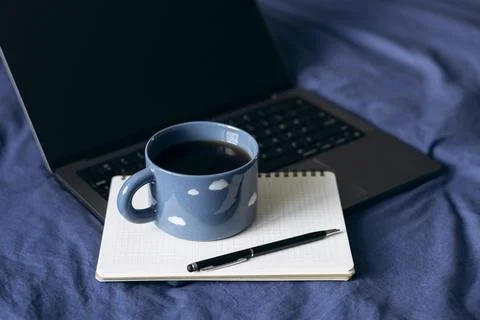Notebook and coffee on blue bed for calm morning lifestyle, copy space. Stock Photos