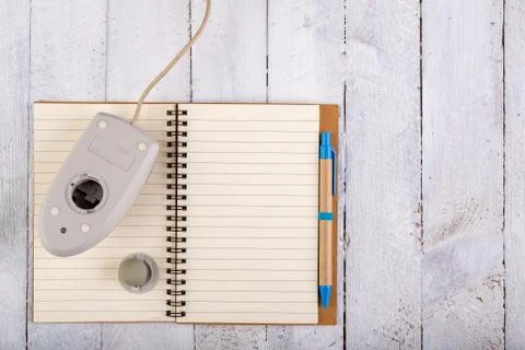 Notebook and old mouse on a white table. Office accessories for work. Stock Photos