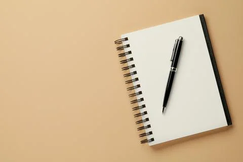 Notebook and pen on beige background, top view. Space for text Stock Photos
