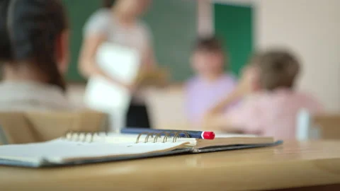 Notebook and pencil on desk with blurred classroom background Video stock 339330977