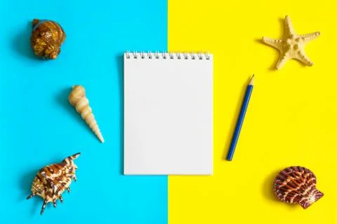 Notebook and pencil with seashells and sea stars on blue and yellow paper bac Stock Photos