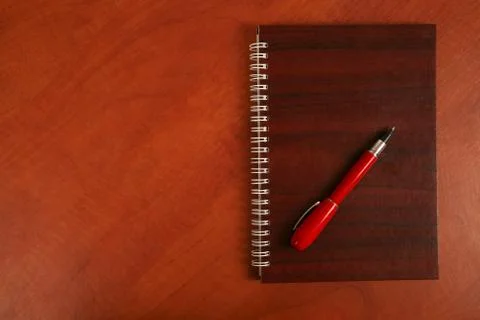 Notebook and a red pen lying on wooden desk Stock Photos