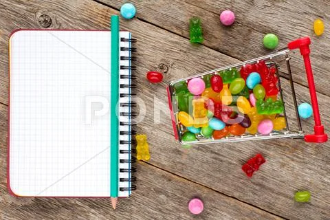 Notebook And Shopping Cart Full Of Candies