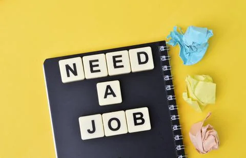 Notebook and square letters with text NEED A JOB. Stock Photos