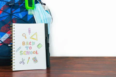 Notebook with back to school drawing. Study backpack with mask and gel. Stock Photos