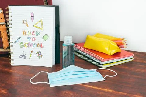 Notebook with back to school drawing. Study utensils, mask and gel. Stock Photos