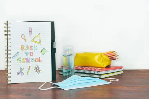 Notebook with back to school drawing. Study utensils, mask and gel. Stock Photos