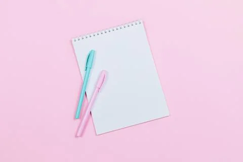 Notebook with blank page and two pens on a pink background. Flat lay. Place f Stock Photos