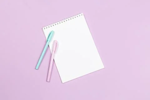 Notebook with blank page and two pens on a violet background. Flat lay. Place Stock Photos