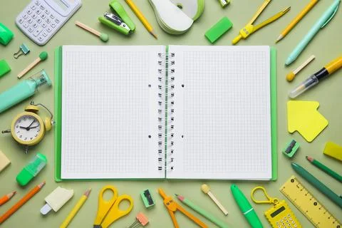 Notebook with blank pages and different school stationery supplies on green b Stock Photos