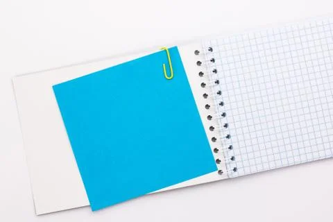 Notebook with a blue sheet of colored paper with a yellow paper clip Stock Photos