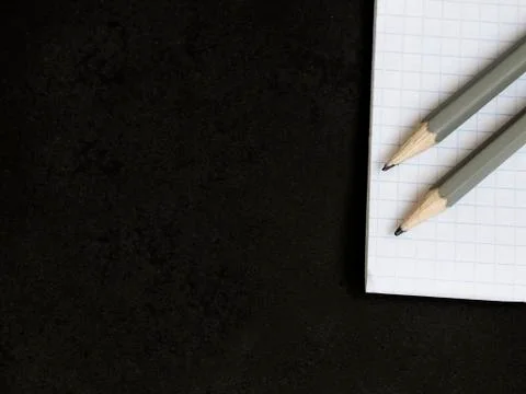 Notebook in a cage with pencils lying on a black table Stock Photos
