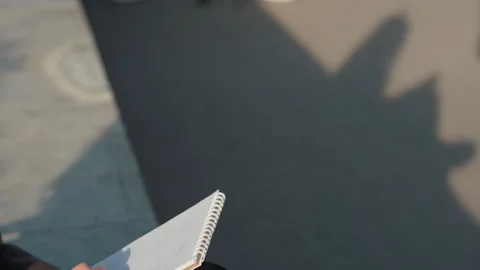 Notebook casts shadow. Warm afternoon light highlighting pavement texture Stock Footage 331735847