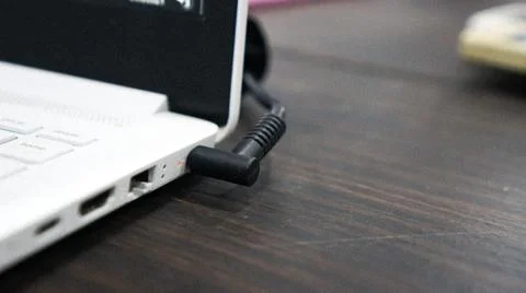 The notebook is charging the battery with a plugged power cable Stock Photos