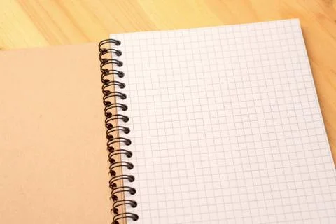 Notebook with checkered sheets on a wooden table. Top view Stock Photos