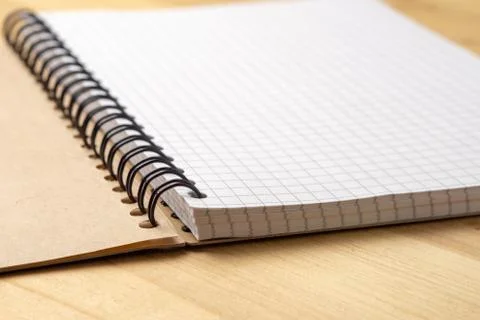Notebook with checkered sheets on a wooden table. Side view Foto stock