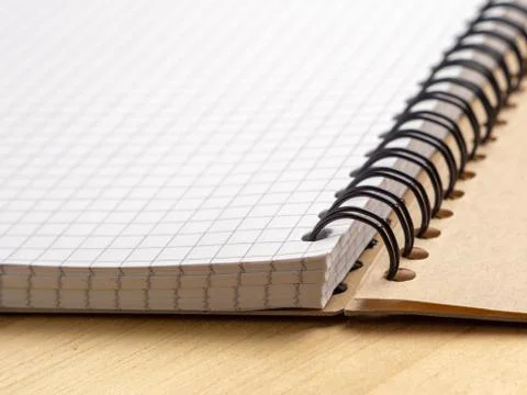 Notebook with checkered sheets on a wooden table. Side view Stock-Fotos