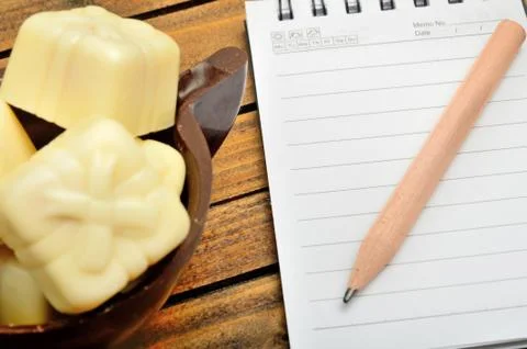 Notebook with chocolate gift on table Stock Photos