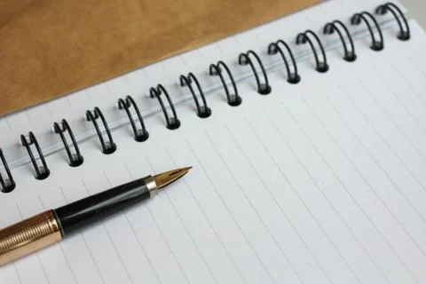 A notebook with clean sheets, an envelope and a gold pen on the table Stock Photos