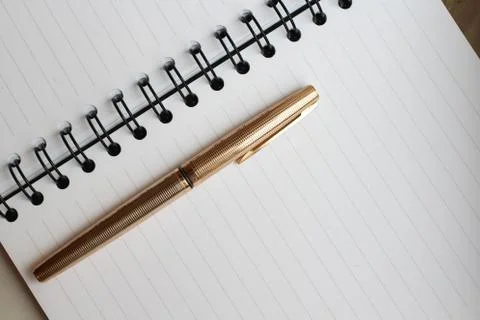 A notebook with clean sheets, an envelope and a gold pen on the table Stock Photos
