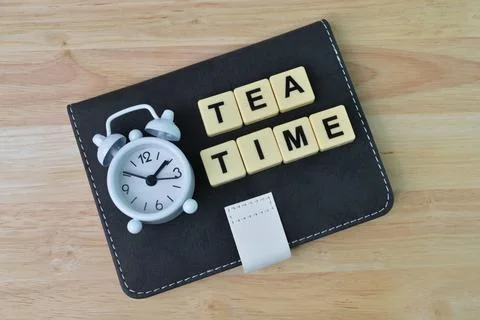 Notebook, clock and square letters with text TEA TIME. Stock Photos