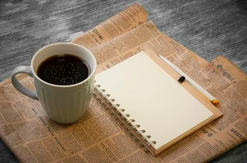 Notebook, coffee beans, cup of cofee and newspaper Stock Photos