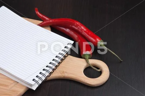 Notebook for cooking recipes and red chili peppers Stock Photos