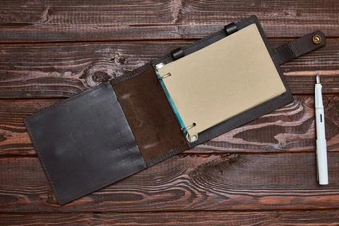 Notebook with craft paper in an unfolded form lies on a wooden surface with a Stock Photos
