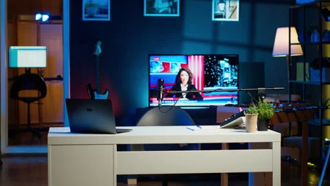 Notebook device sitting on table, news broadcast running on TV in background Stock Footage 306693586